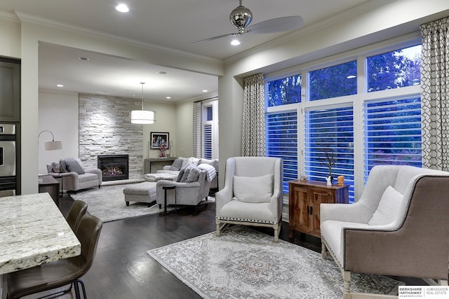 living room featuring crown molding, dark hardwood / wood-style floors, ceiling fan, and a fireplace