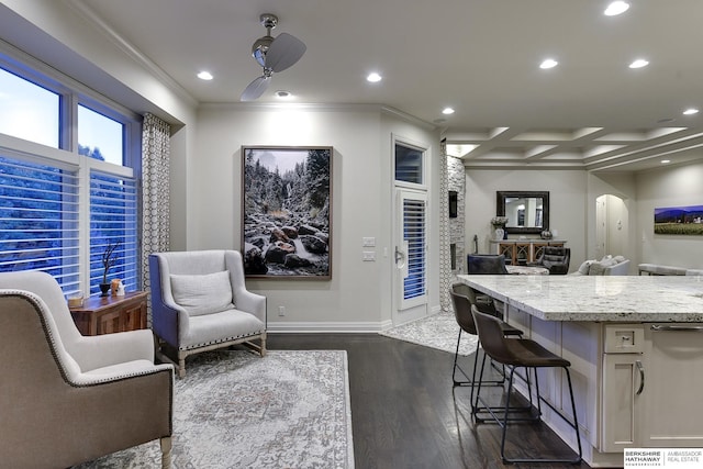 interior space featuring a breakfast bar area, coffered ceiling, ceiling fan, crown molding, and dark wood-type flooring