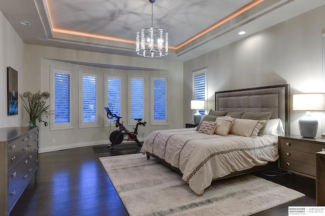 bedroom featuring an inviting chandelier, dark hardwood / wood-style floors, and a raised ceiling