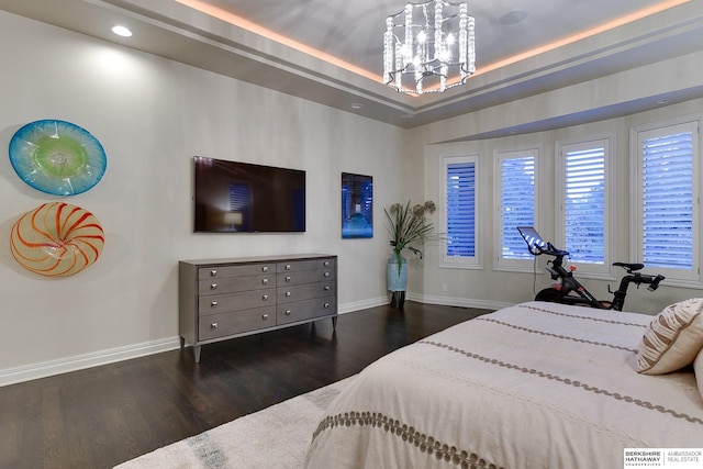 bedroom featuring dark hardwood / wood-style flooring, a tray ceiling, and a chandelier