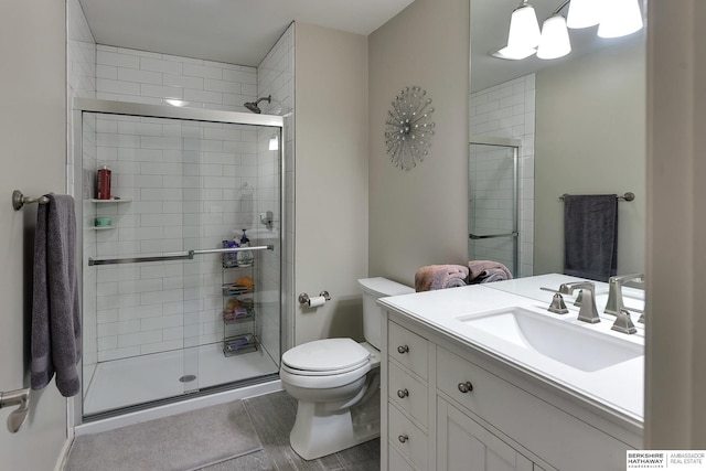 bathroom featuring vanity, a shower with shower door, and toilet