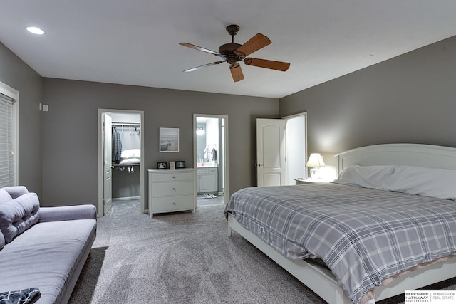 carpeted bedroom featuring ceiling fan, connected bathroom, and a spacious closet