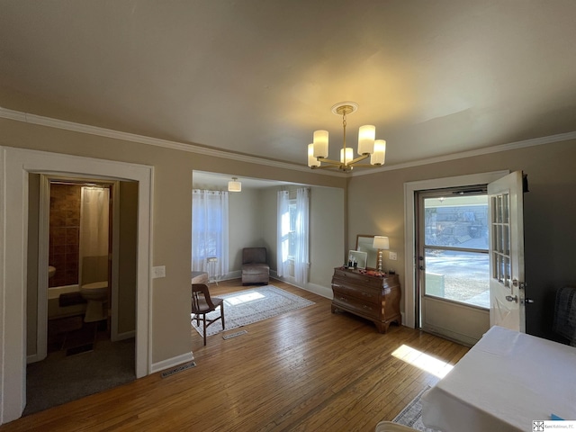 sitting room with crown molding, an inviting chandelier, and hardwood / wood-style floors
