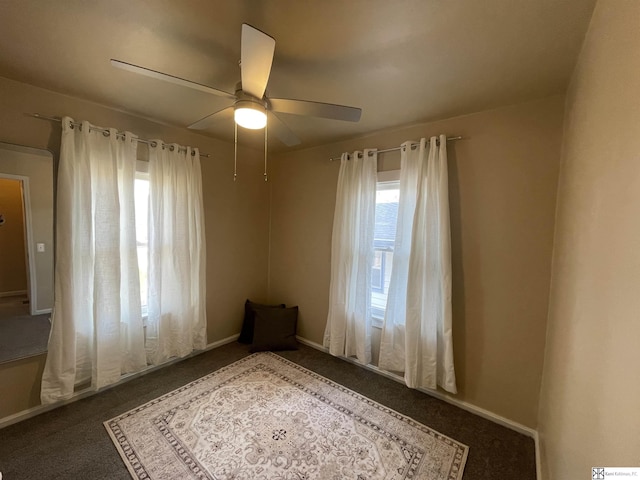 empty room featuring ceiling fan and dark carpet