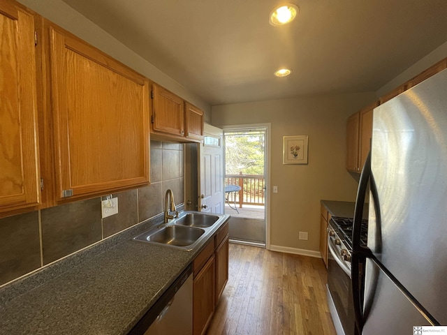 kitchen featuring tasteful backsplash, sink, light hardwood / wood-style flooring, and stainless steel appliances