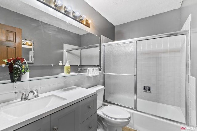 full bathroom featuring bath / shower combo with glass door, decorative backsplash, vanity, toilet, and a textured ceiling