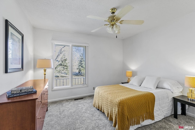 bedroom with ceiling fan, carpet, and a textured ceiling