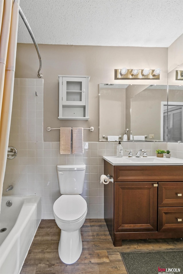 full bathroom with wood-type flooring, tiled shower / bath combo, a textured ceiling, and tile walls