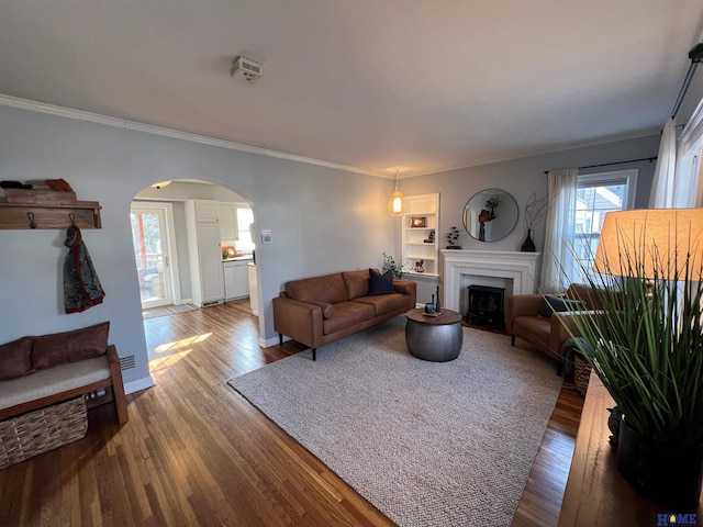 living room featuring hardwood / wood-style flooring, crown molding, and built in shelves