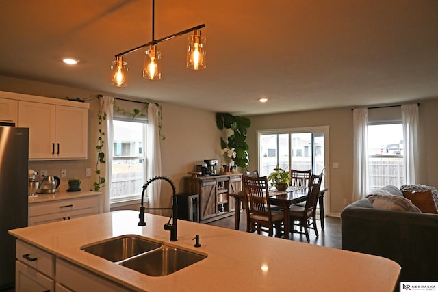 kitchen featuring sink, stainless steel fridge, hanging light fixtures, dark hardwood / wood-style floors, and white cabinets