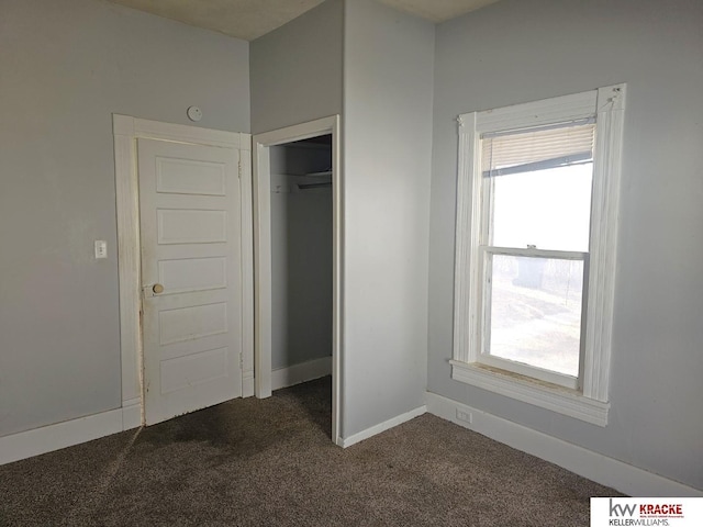 unfurnished bedroom with a closet and dark colored carpet