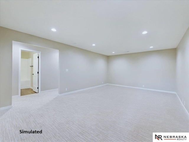 spare room featuring recessed lighting, light colored carpet, and baseboards