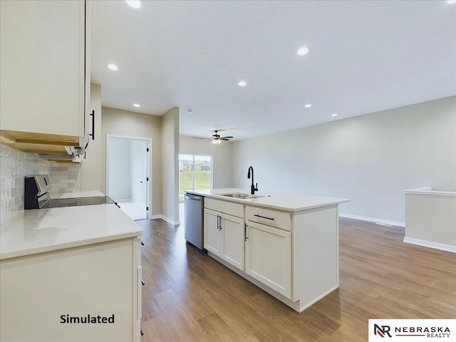 kitchen with light wood finished floors, an island with sink, a sink, stainless steel appliances, and backsplash