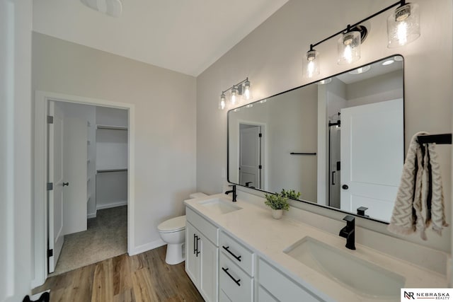 bathroom featuring double vanity, a sink, toilet, and wood finished floors