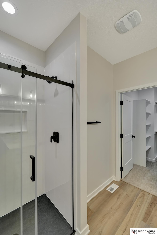 bathroom featuring visible vents, a shower stall, baseboards, and wood finished floors