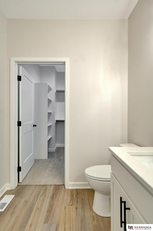 bathroom featuring toilet, wood finished floors, visible vents, vanity, and baseboards