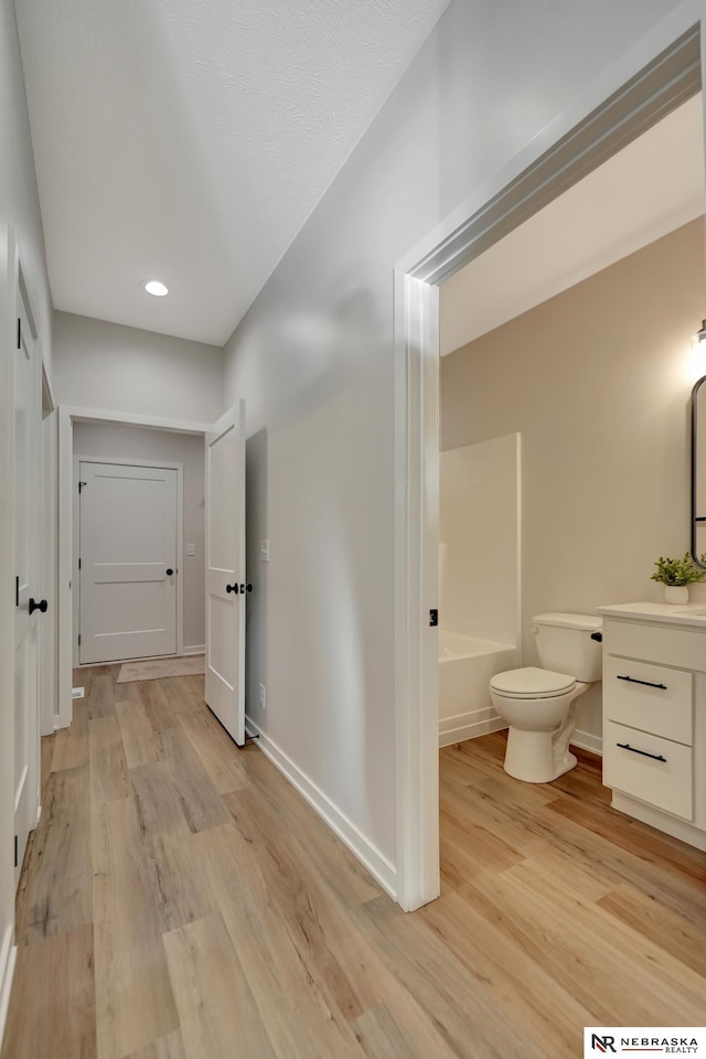 full bath with toilet, baseboards, wood finished floors, and vanity