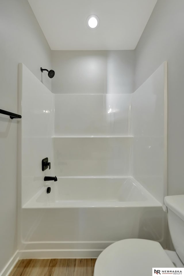 bathroom with tub / shower combination, toilet, and wood finished floors