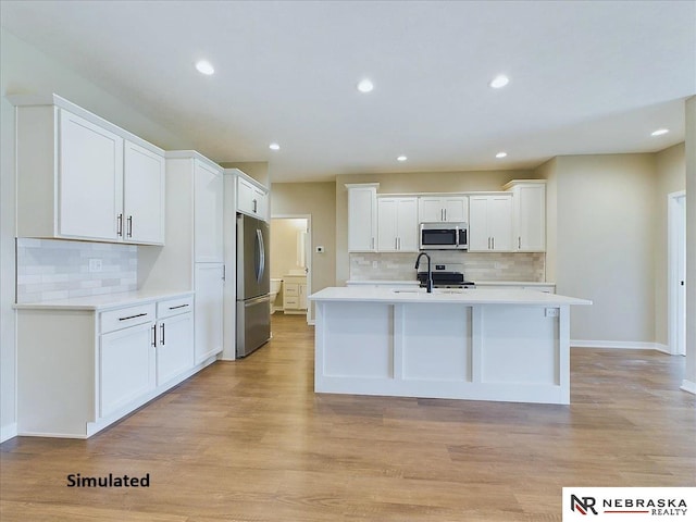 kitchen with a center island with sink, stainless steel appliances, light countertops, light wood-style floors, and white cabinetry