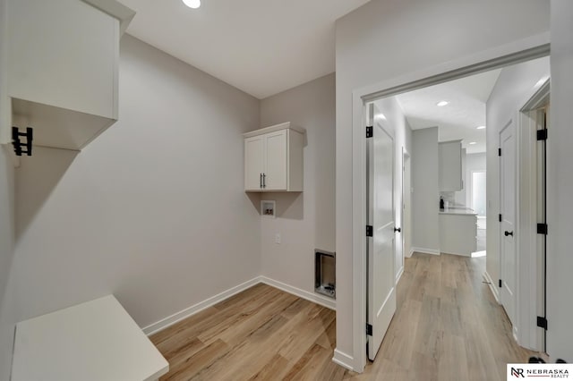 clothes washing area with baseboards, hookup for a washing machine, and light wood-style floors