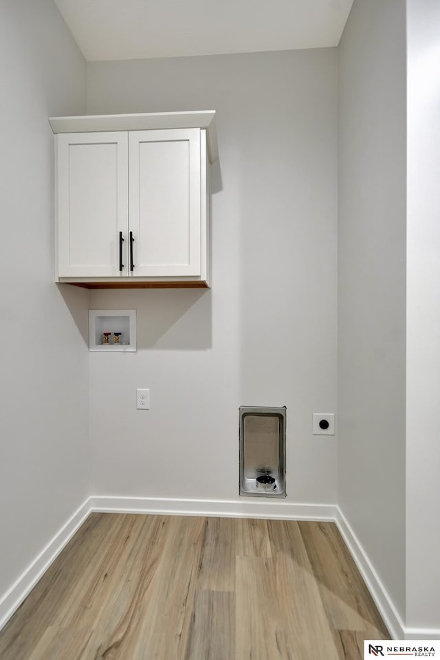 clothes washing area featuring cabinet space, light wood finished floors, baseboards, hookup for a washing machine, and hookup for an electric dryer