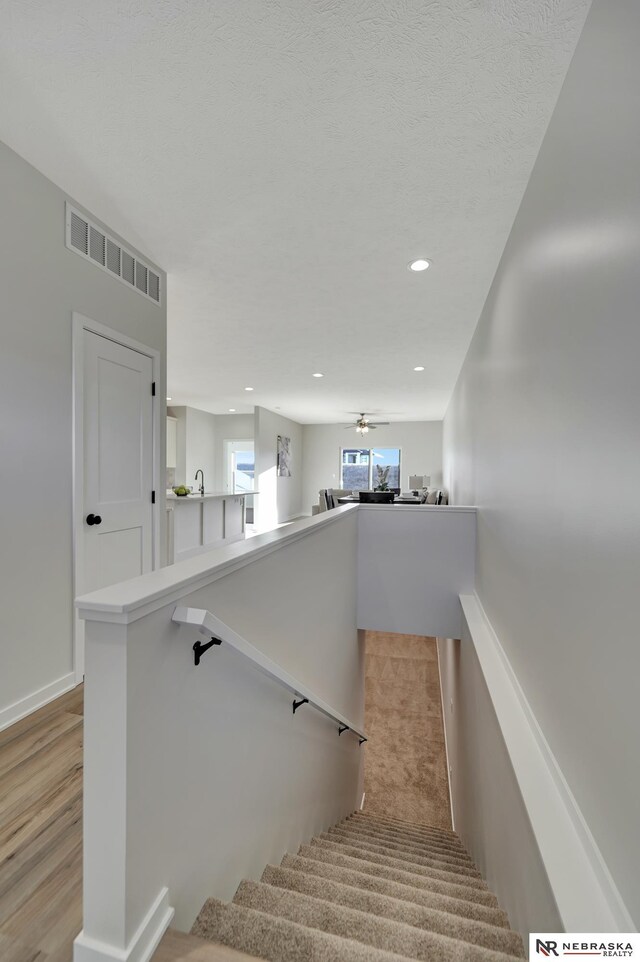 stairway featuring ceiling fan, recessed lighting, wood finished floors, visible vents, and baseboards