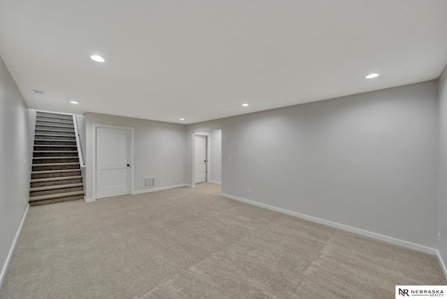 finished basement with light carpet, stairway, visible vents, and baseboards