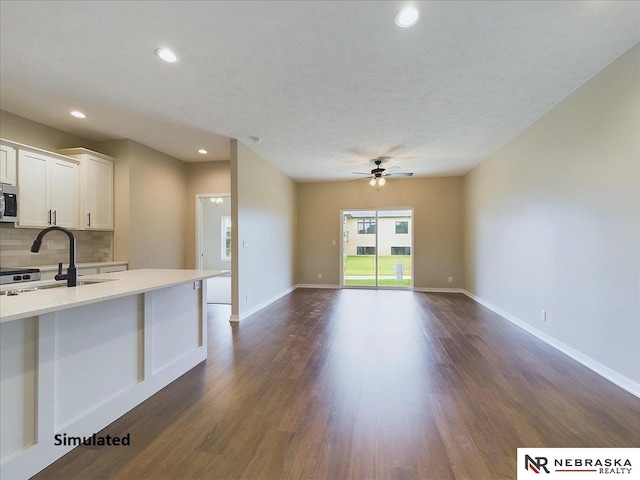 kitchen featuring dark wood-type flooring, light countertops, stainless steel microwave, and decorative backsplash