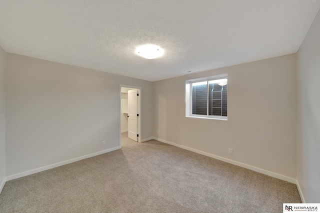 unfurnished room with baseboards, a textured ceiling, and light colored carpet