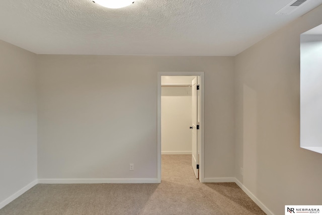 spare room featuring baseboards, visible vents, a textured ceiling, and light colored carpet