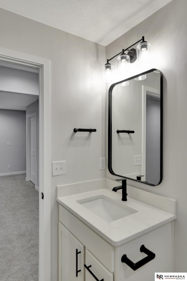 bathroom featuring baseboards, vanity, and a textured ceiling