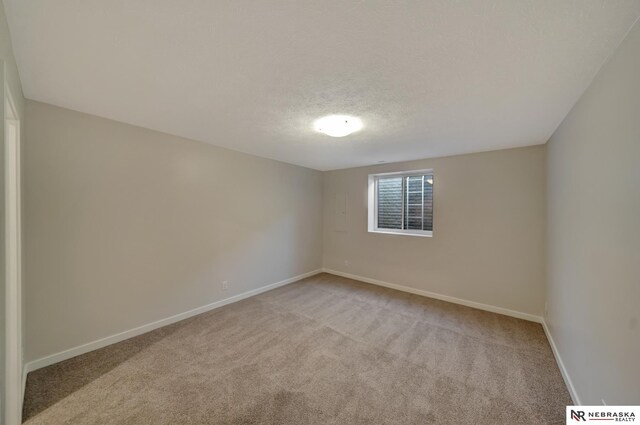 unfurnished room with baseboards, a textured ceiling, and light colored carpet