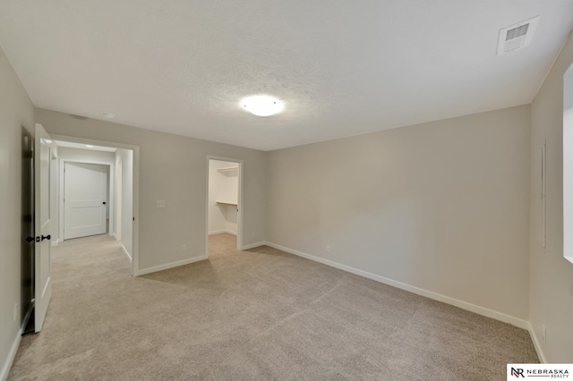 unfurnished bedroom featuring light carpet, baseboards, visible vents, and a textured ceiling