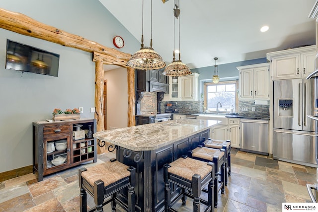 kitchen featuring a breakfast bar, a kitchen island, pendant lighting, stainless steel appliances, and light stone countertops