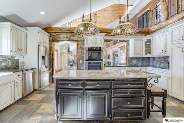 kitchen featuring light stone countertops, appliances with stainless steel finishes, a center island, and decorative light fixtures