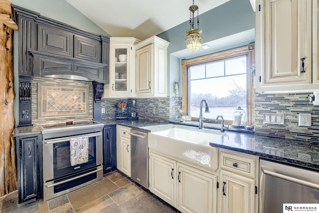 kitchen with sink, appliances with stainless steel finishes, decorative light fixtures, vaulted ceiling, and dark stone counters