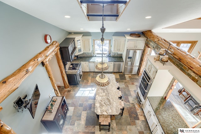 kitchen with backsplash, stainless steel appliances, and white cabinets