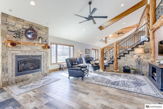 living room with lofted ceiling with beams, a stone fireplace, hardwood / wood-style flooring, and ceiling fan