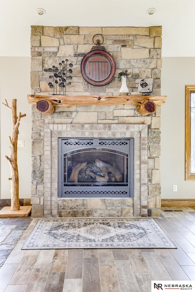 details with a stone fireplace and wood-type flooring