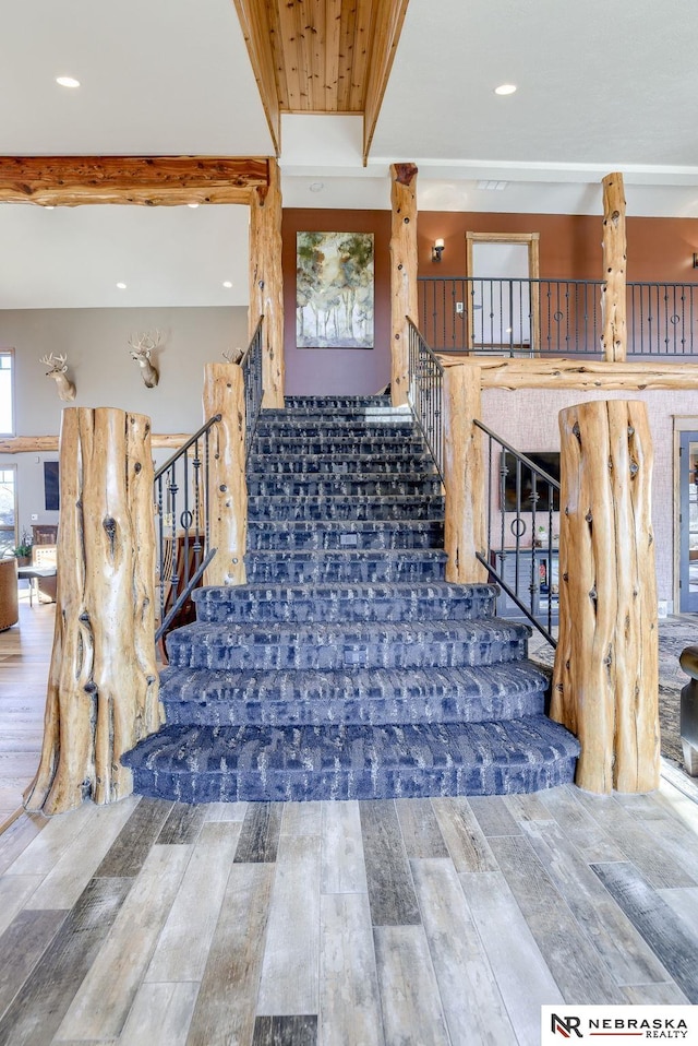 stairway with wood-type flooring and beam ceiling