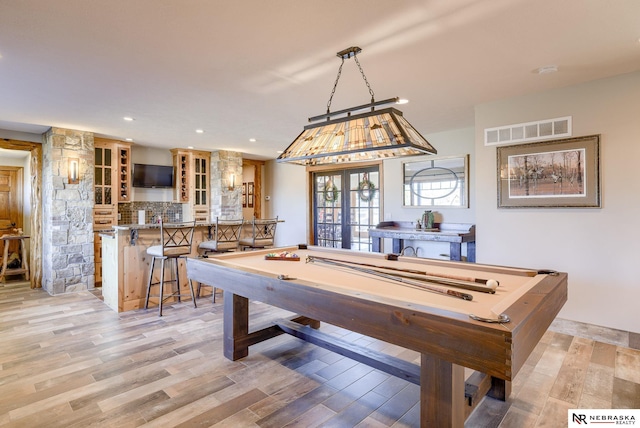 game room with french doors, pool table, bar area, and light wood-type flooring