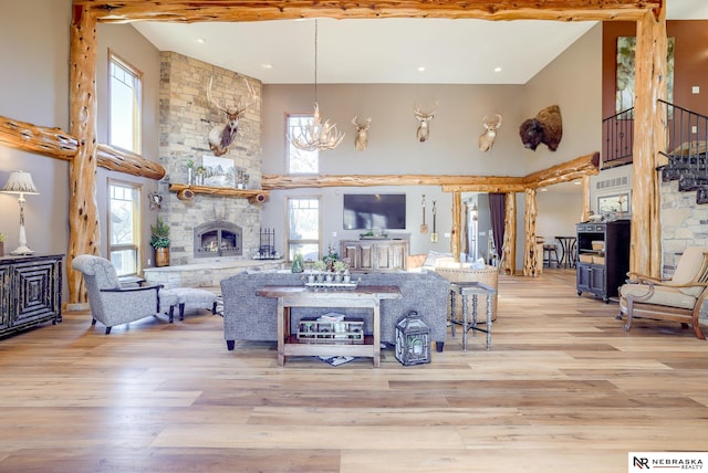 living room with a fireplace, a wealth of natural light, light hardwood / wood-style flooring, and a notable chandelier