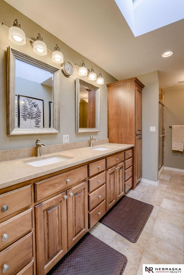 bathroom with a shower with door, vanity, tile patterned flooring, and a skylight