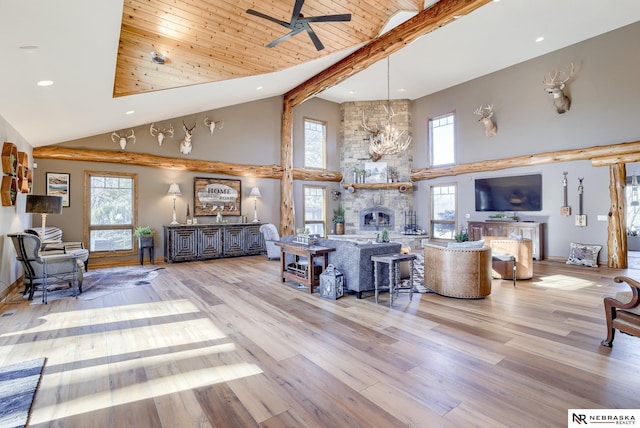 living room with a stone fireplace, high vaulted ceiling, ceiling fan, wooden ceiling, and light hardwood / wood-style flooring