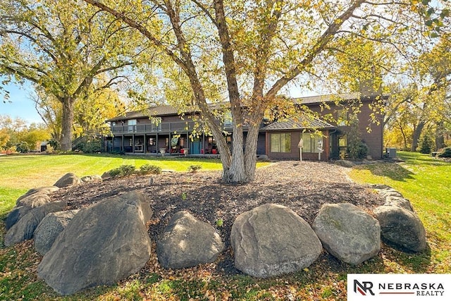 back of property featuring a wooden deck and a yard