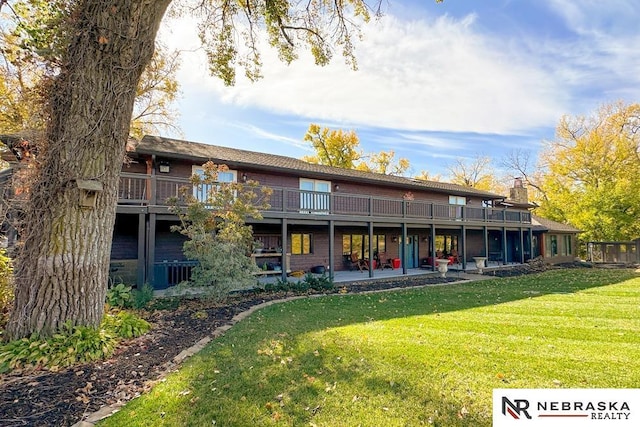 rear view of house featuring a wooden deck, a yard, and a patio