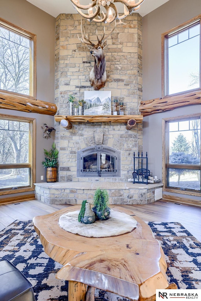 unfurnished living room featuring a stone fireplace, plenty of natural light, and a towering ceiling