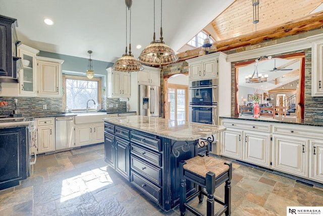 kitchen with decorative light fixtures, sink, dark stone counters, a center island, and stainless steel appliances