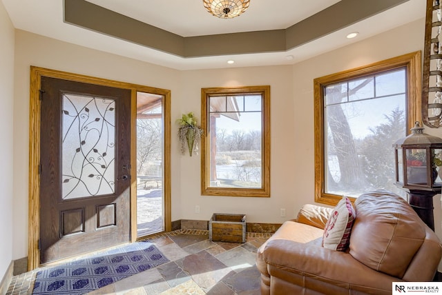 foyer entrance with a tray ceiling and a healthy amount of sunlight