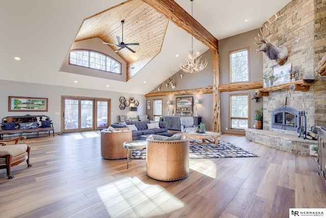 living room featuring high vaulted ceiling, a fireplace, light hardwood / wood-style floors, and a healthy amount of sunlight